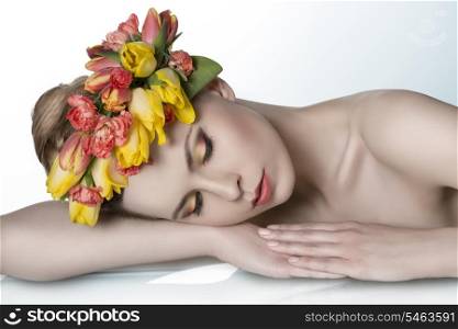 portrait of sensual blonde woman with colorful make-up, fresh skin, naked shoulders and spring floral garland on the head. Lying on table