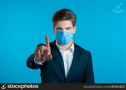 Portrait of serious businessman in professional suit showing rejecting gesture by stop finger sign. Man isolated on blue background. Portrait of serious businessman in professional suit and medical mask showing rejecting gesture by stop finger sign. Man isolated on blue background.