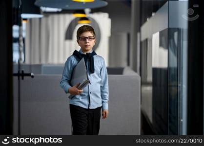 Portrait of serious child businessman holding paper document folder in hand walking in office. Portrait of serious child businessman in office