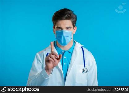 Portrait of serious doctor in professional medical white coat and mask showing rejecting gesture disapproving with no finger sign. Denying, Disagree. Doc man isolated on blue background. Portrait of serious doctor in professional medical white coat and mask showing rejecting gesture disapproving with no finger sign. Denying, Disagree. Doc man isolated on blue background.