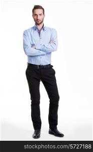 Portrait of serious man in blue shirt and black pants with crossed arms - isolated on white.&#xA;