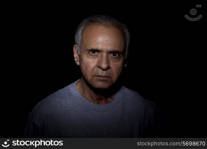 Portrait of serious man over black background