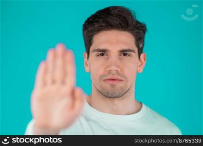 Portrait of serious man showing rejecting gesture by stop palm hand sign. Guy isolated on blue background. High quality photo. Portrait of serious man showing rejecting gesture by stop palm hand sign. Guy isolated on blue background.
