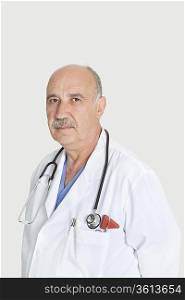 Portrait of serious senior medical practitioner over gray background