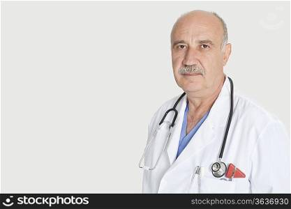 Portrait of serious senior medical practitioner with stethoscope over gray background