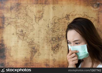 Portrait of serious young Asian girl wearing a mask on world map background. Prevent pollution and disease concept.