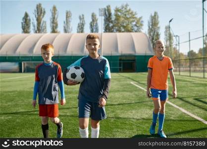 Portrait of serious young boy football player with soccer ball standing on field with teammates. Portrait of serious young soccer player standing on field with teammates