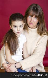 Portrait of seven year old daughter and young mother on red isolated