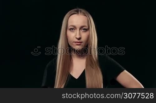 Portrait of sexy attractive female with long blond hair with flirty look looking at camera isolated on black background. Awesome woman flirting with the camera and playfully smiling. Human facial expression and emotion.