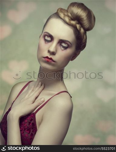 portrait of sexy blonde lady with valentines heart shaped make-up, elegant creative hairdo and red dress. Romantic expression