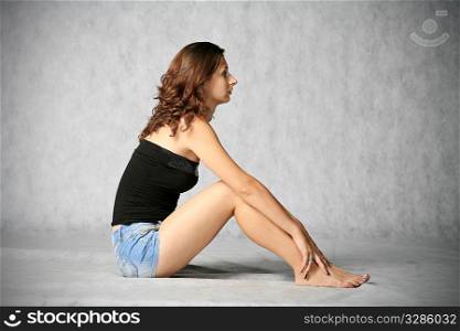 portrait of sexy brunette sitting on the grey background