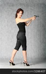 portrait of sexy redhead with pistol on the grey background