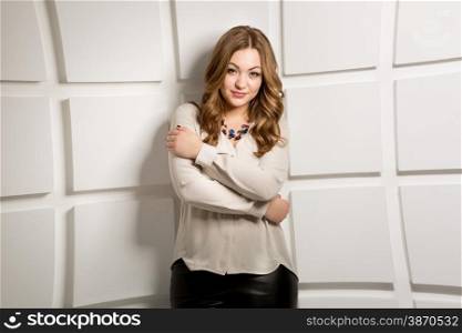 Portrait of sexy slim woman in white shirt posing against brick wall at studio