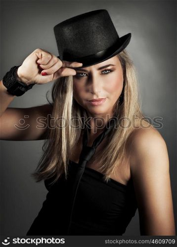 Portrait of sexy stylish attractive model wearing black hat and tie posing over gray background in the studio, luxury fashion look