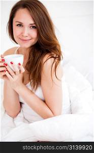 portrait of sexy woman drinking a cup of tea on the bed at home, isolated on white background