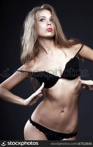 Portrait of sexy woman in black underwear on a dark wall
