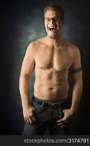Portrait of shirtless adult Caucasian man on studio background laughing.