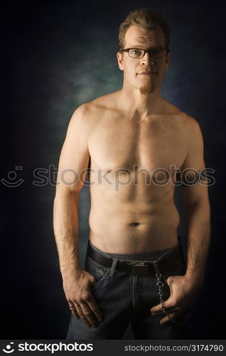 Portrait of shirtless adult Caucasian man on studio background looking at viewer.