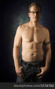 Portrait of shirtless adult Caucasian man on studio background looking at viewer.