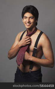 Portrait of shirtless man in suspenders wearing tie