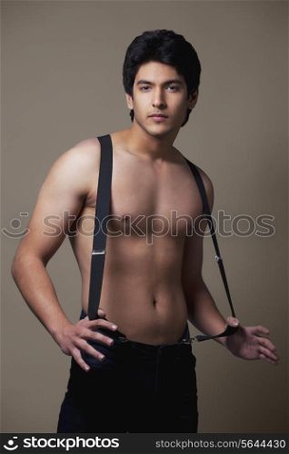 Portrait of shirtless man wearing suspenders