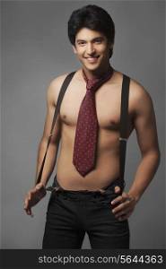 Portrait of shirtless man wearing suspenders and tie