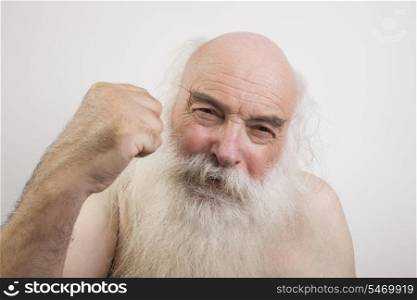 Portrait of shirtless senior man throwing a punch against white background