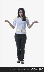 Portrait of shocked businesswoman covered with adhesive notes standing over white background