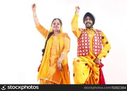 Portrait of Sikh couple doing bhangra dance