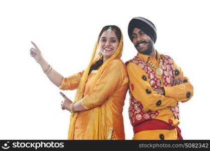 Portrait of Sikh couple standing back to back