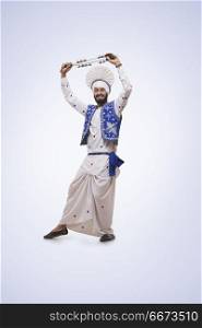 Portrait Of Sikh man Dancing and Holding A Chimta