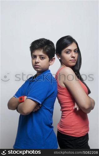 Portrait of sister and brother standing back to back