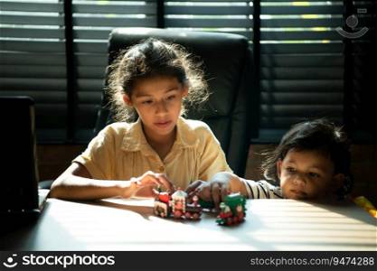 Portrait of Sister and little brother in the office room of house, They are having fun playing with toy trains together.