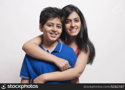 Portrait of Sister with arms around her brother looking at camera and smiling