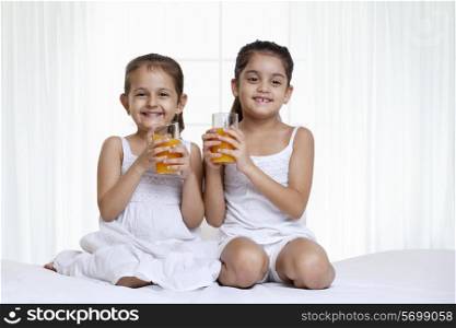 Portrait of sisters holding glass of juice