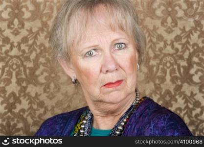 Portrait of skeptical senior woman in front of gold background