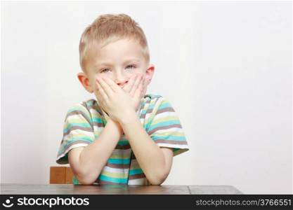 Portrait of sleepy tired blond cute boy child kid yawning covering mouth with hands. At home.