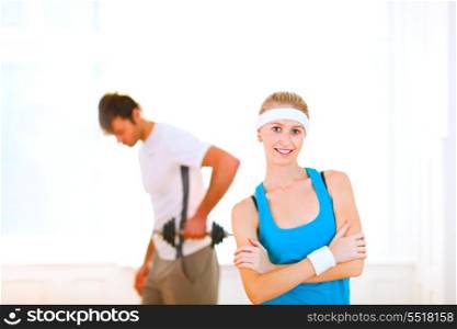 Portrait of slim girl in sportswear and man making sport exercises in background&#xA;
