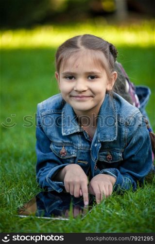 Portrait of small girl pointing at tablet touchscreen on grass