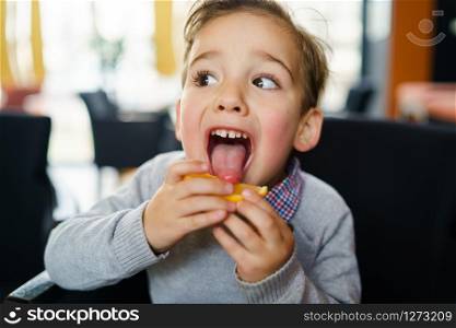 Portrait of small three years old caucasian boy child sitting in the chair licking a slice of lemon protruding tongue making faces