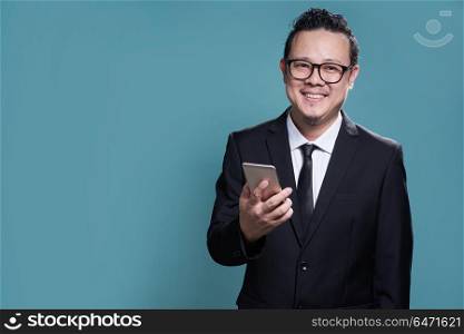 Portrait of smile asian businessman in suit with using smartphone . isolated on light blue background .