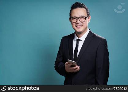 Portrait of smile asian businessman in suit with using smartphone . isolated on light blue background .