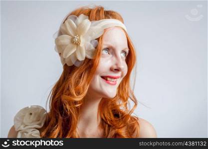 Portrait of smiling a beautiful red haired woman with flower in her hair. Fashion photo