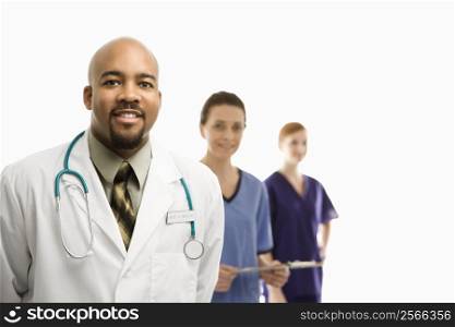 Portrait of smiling African-American man and Caucasian women medical healthcare workers in uniforms standing against white background.