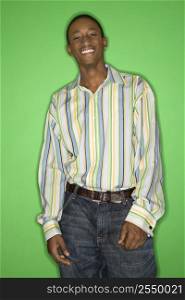Portrait of smiling African-American teen boy standing in front of green background.