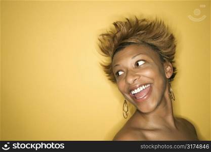 Portrait of smiling African-American young adult woman on yellow background.