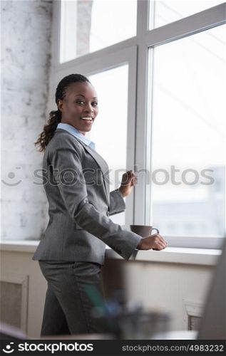 Portrait of smiling african business woman at her office with coffee cup celebrating success and expressing happiness joy and positivity