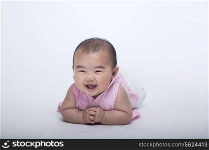 Portrait of smiling and laughing baby lying down, studio shot, white background