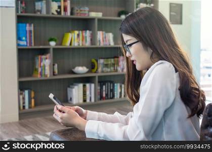Portrait of smiling asian beautiful young businesswoman working with smart mobile phone in the modern living room, lifestyle concept