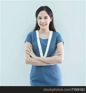 Portrait of smiling asian businesswoman standing with arms folded and looking at camera isolated over grey background